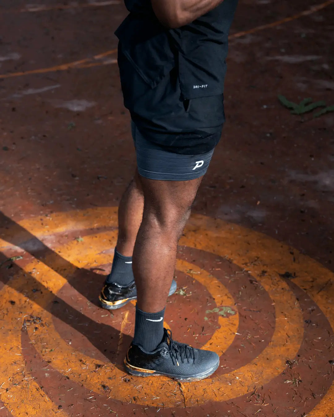 Male athlete playing basketball in black Middy shorts, demonstrating the no-slip fit and secure storage.