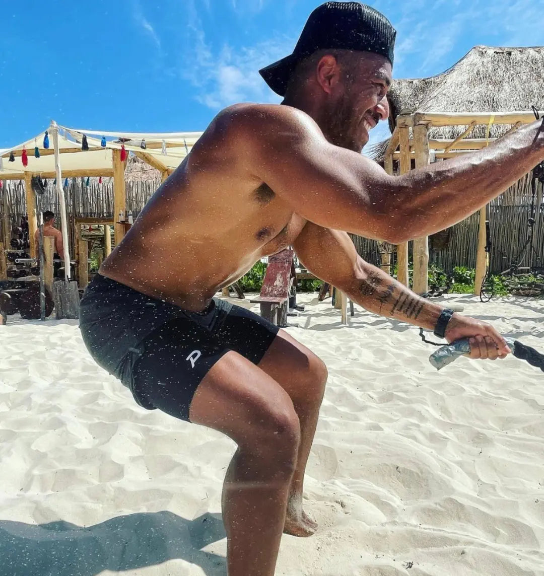 Athlete sprinting on sand in black Middy shorts, proving the fabric's quick-dry properties in tough conditions.