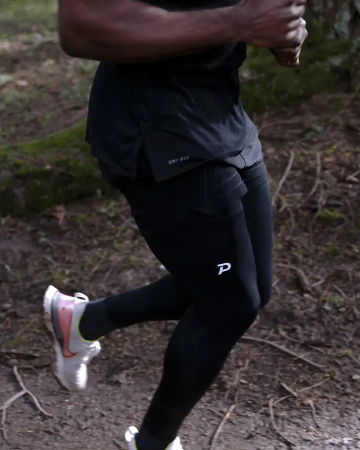 Close-up of an athlete running in Strider tights, showing the secure phone pocket and moisture-wicking properties of Swingloft fabric.