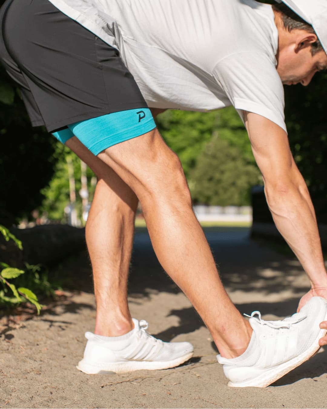 Runner stretching in blue compression Middy shorts, demonstrating the 4-way stretch and muscle recovery support.