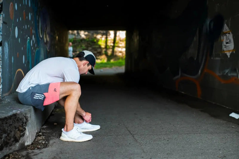 Runner tying shoes in the tunnel wearing Pacterra Athletics men's compression shorts with a breathable, moisture-wicking compression fabric.