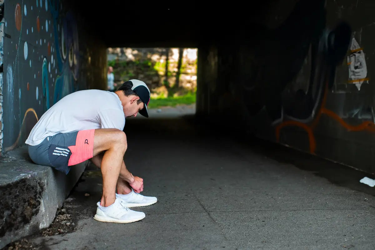 Runner tying shoes in the tunnel wearing Pacterra Athletics men's compression shorts with a breathable, moisture-wicking compression fabric.