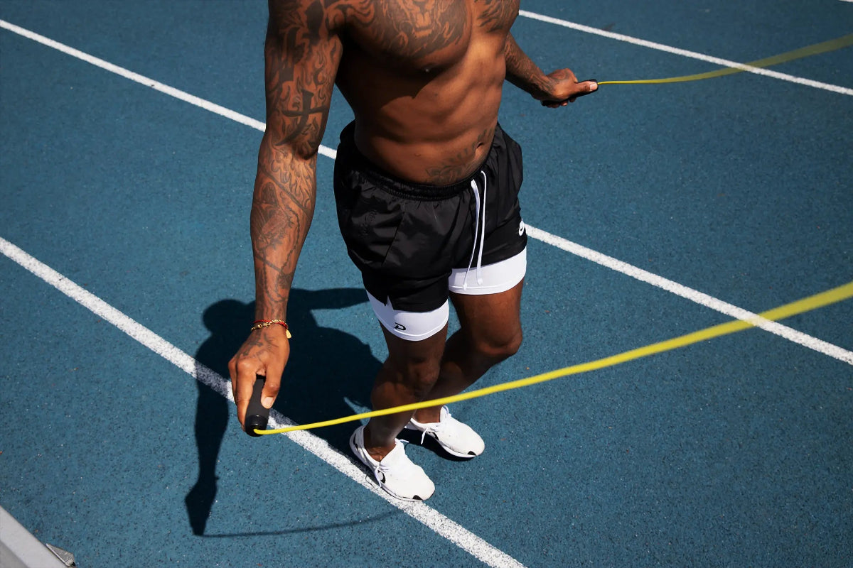 Athlete jump roping in Pacterra Middy performance shorts featuring a secure phone pocket and white compression liner.