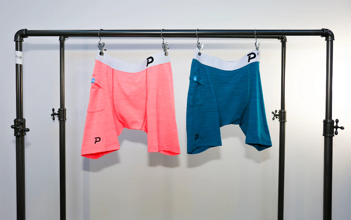 Close-up view of Pacterra Middy men's compression shorts on a rack highlighting the integrated side smartphone pocket.