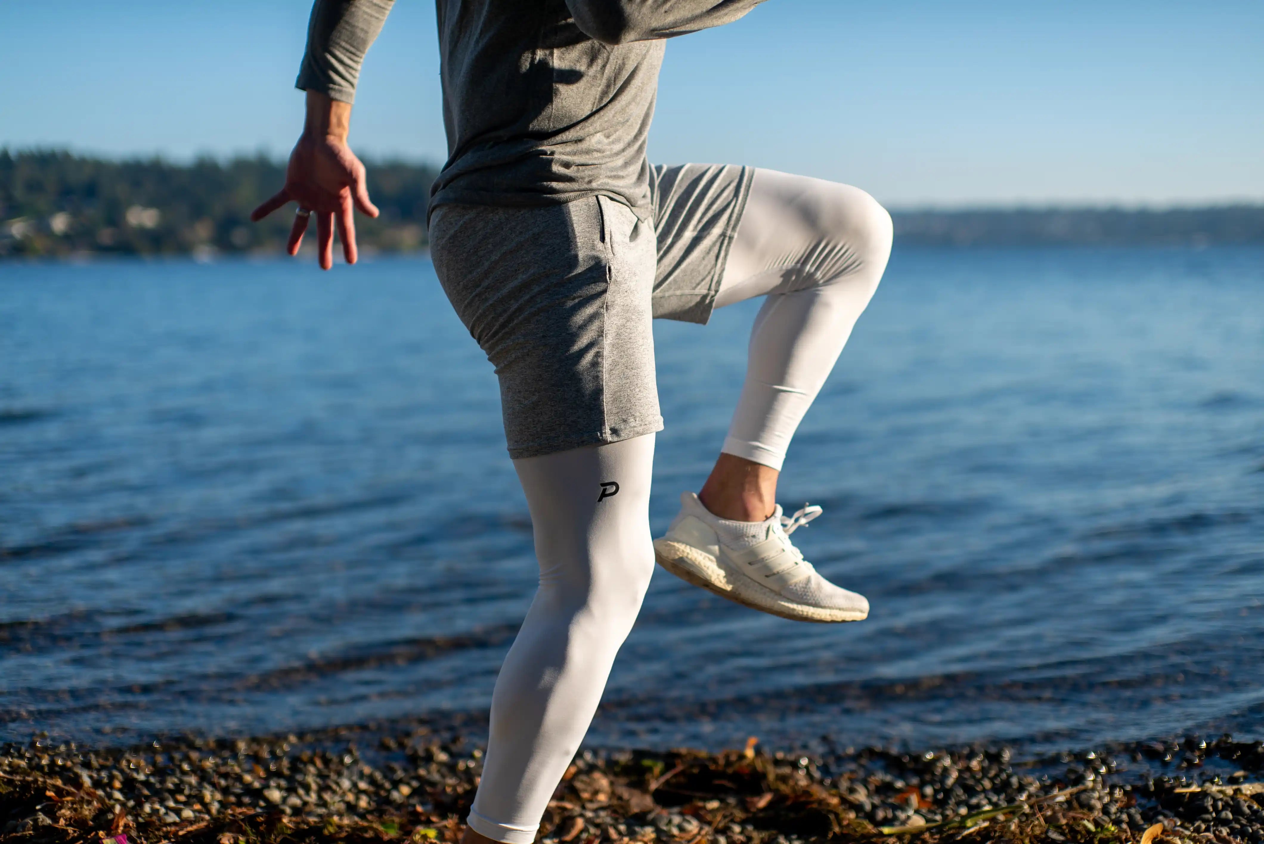 Side view of an athlete running in White Pacterra Strider tights, showcasing the high-opacity Swingloft comfort fabric and secure, tapered athletic fit.