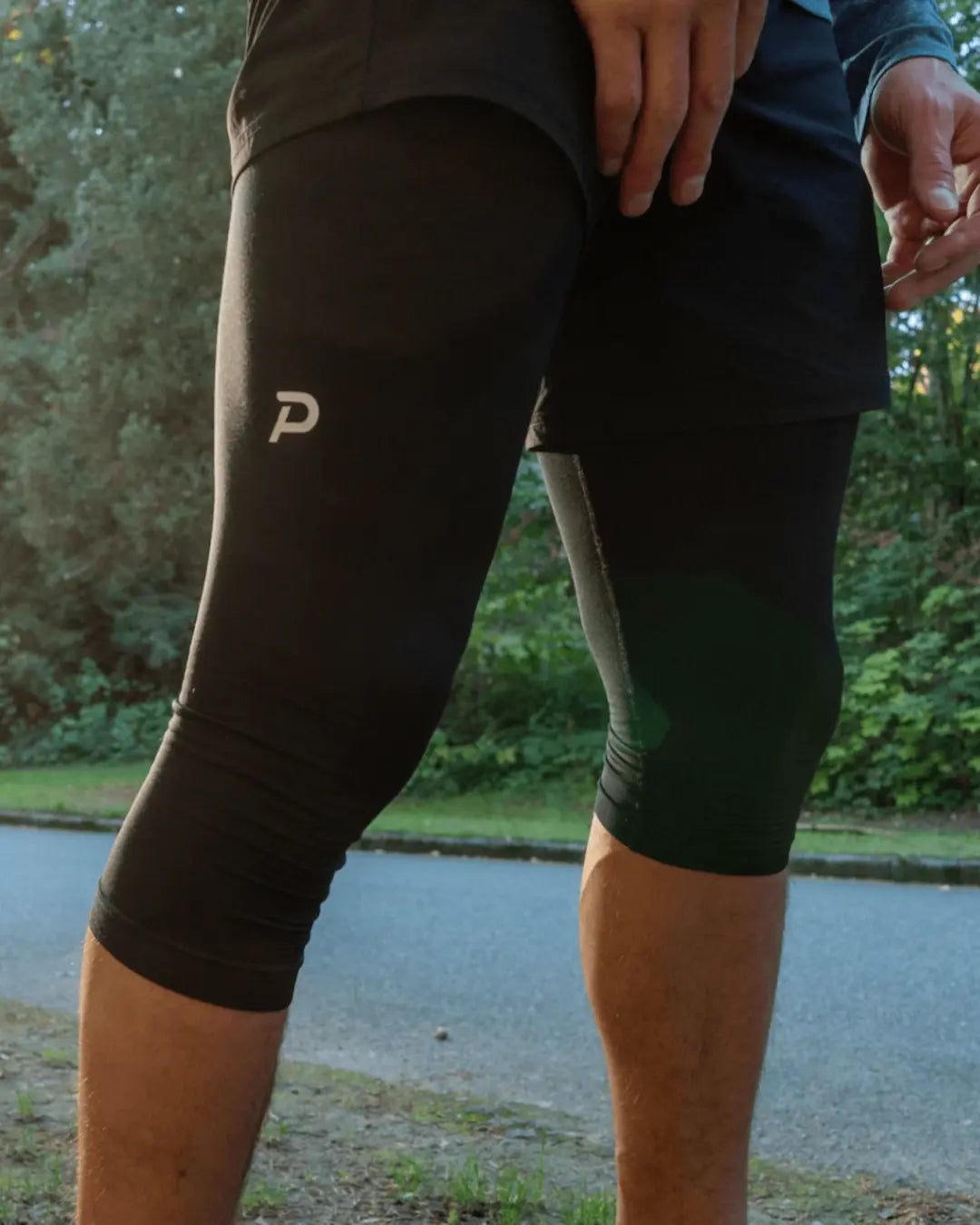 Side view of the black 3/4 Strider men's tights, highlighting the ergonomic seams and streamlined fit for runners.