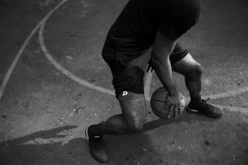 Action shot of an athlete on a basketball court wearing the best and most comfortable Pacterra men's Middy compression shorts.