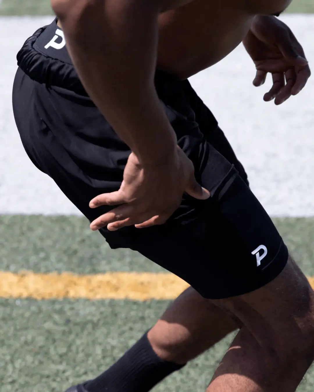 Athlete performing explosive sprints in black Pacterra Middy compression shorts, showing the stay-put leg opening and most comfortable performance fit for field training.