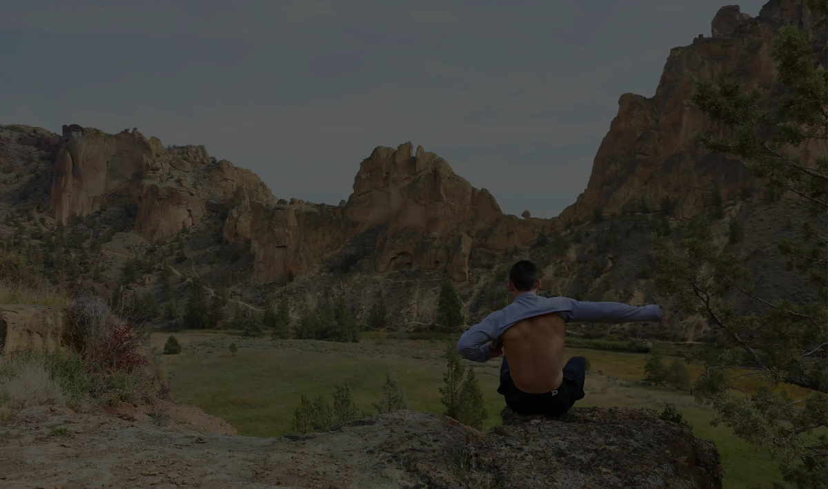 Athlete sitting on a rock overlooking a desert canyon, wearing Pacterra men's compression shorts to demonstrate product versatility from the gym to the trail.