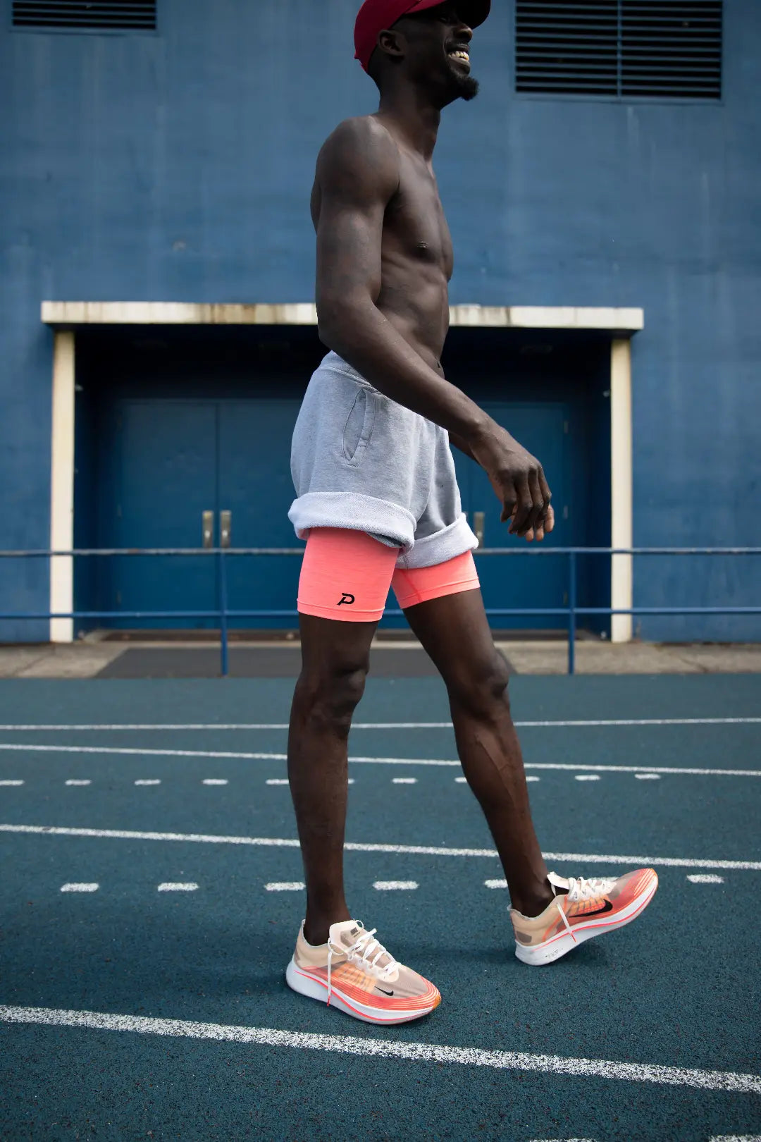 Runner in an urban setting wearing pink Middy shorts layered for a modern, high-visibility athletic look.